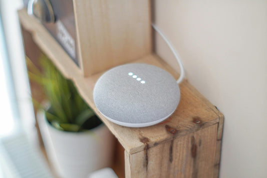 Round grey smart speaker on brown board. Photo by John Tekeridis.